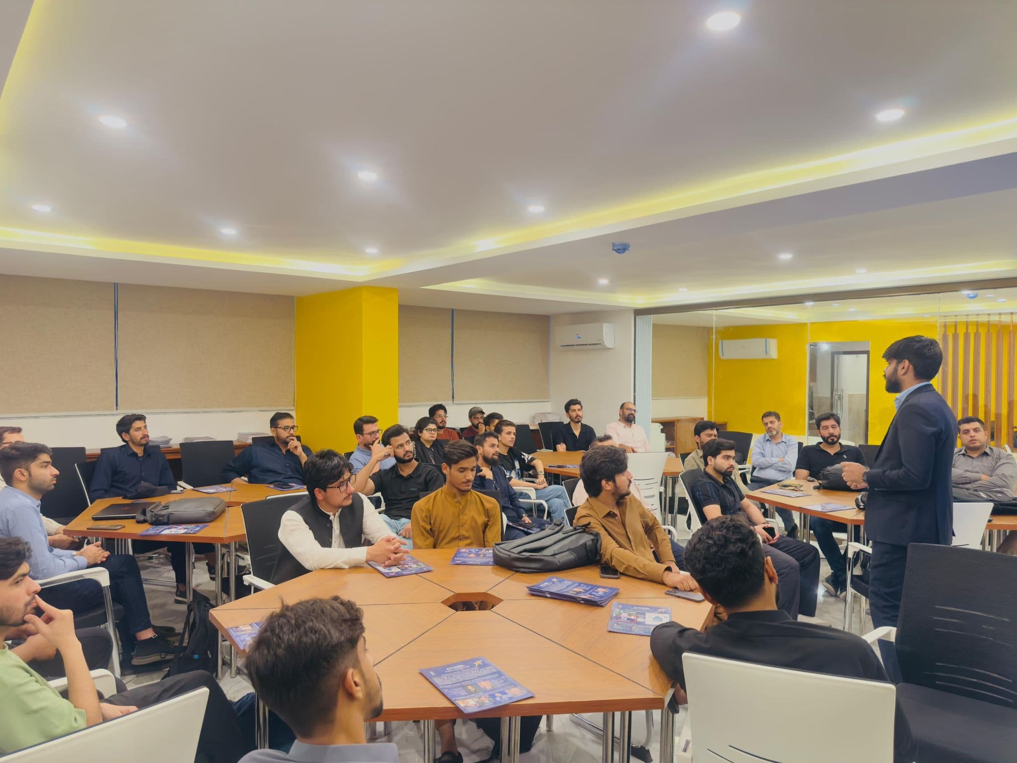 An instructor leading a classroom training session with learners seated around tables
