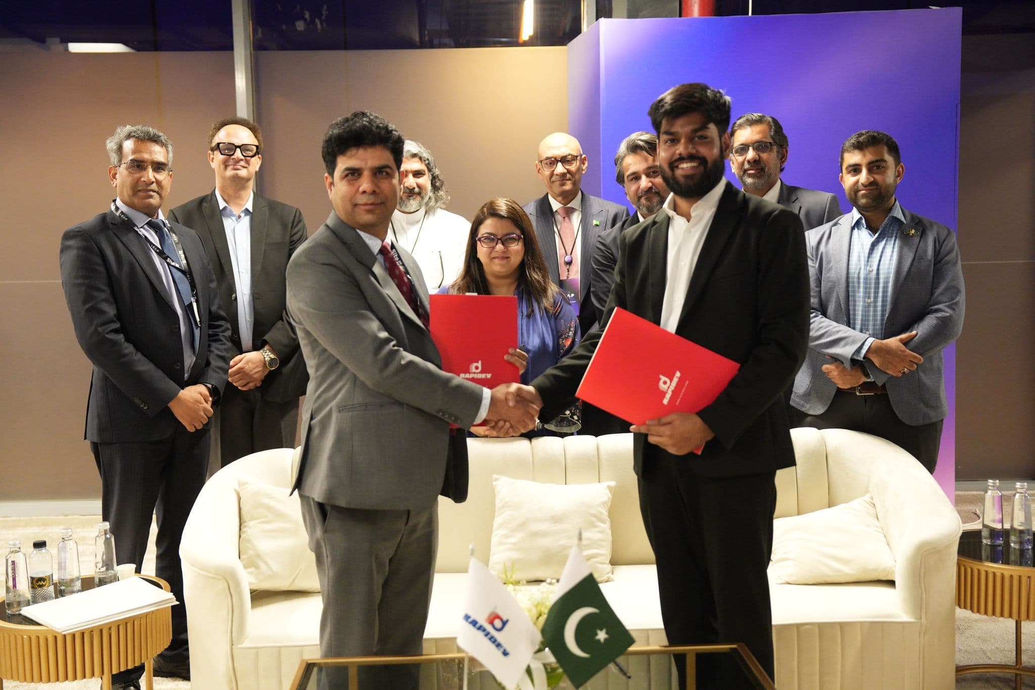 Edversity and Rapidev representatives shaking hands and holding partnership documents at a signing ceremony